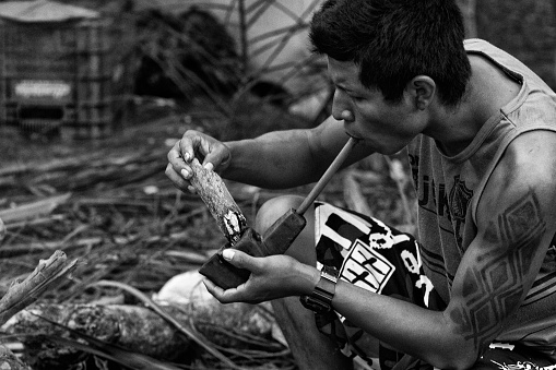 Bertioga, Brazil, April, 19, 2015: Indigenous of ethnic group Guarani from Brazil lighting a pipe during the National Indian Festival held annually in April in the city of Bertioga in the southeast coast of Brazil
