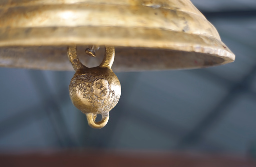 A heavy cast bell in the church bell tower against the yellow-blue sunset sky in the window opening. Close-up. Cherdyn (Northern Ural, Russia). An old bell rings during a service