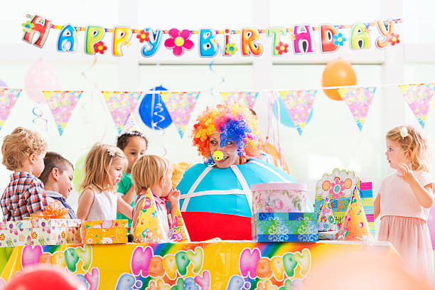 Clown on at child's birthday party. Large group of children playing with clown at birthday party. animator stock pictures, royalty-free photos & images
