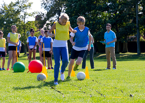 Teenage girls playing soccer on grass pitch