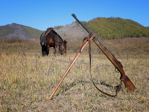 Mongolian hunter left his horse and his hunting rifle