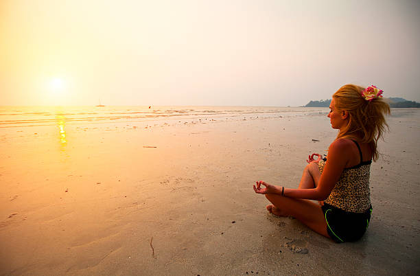 istock Young woman practicing yoga on the beach at sunset 471831519