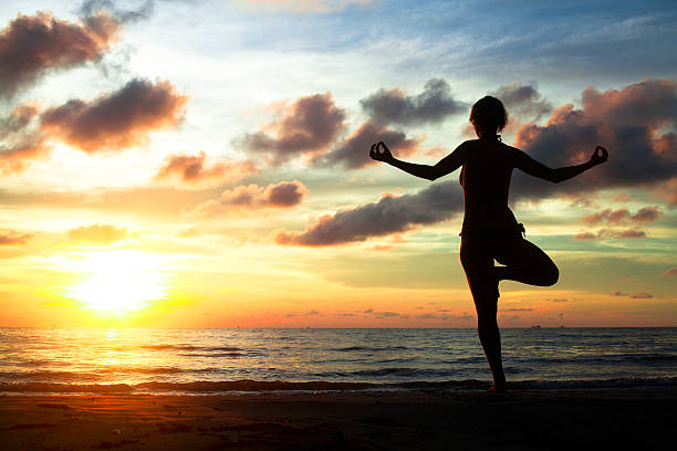 istock Young woman practicing yoga on beach during the sunset 471831541
