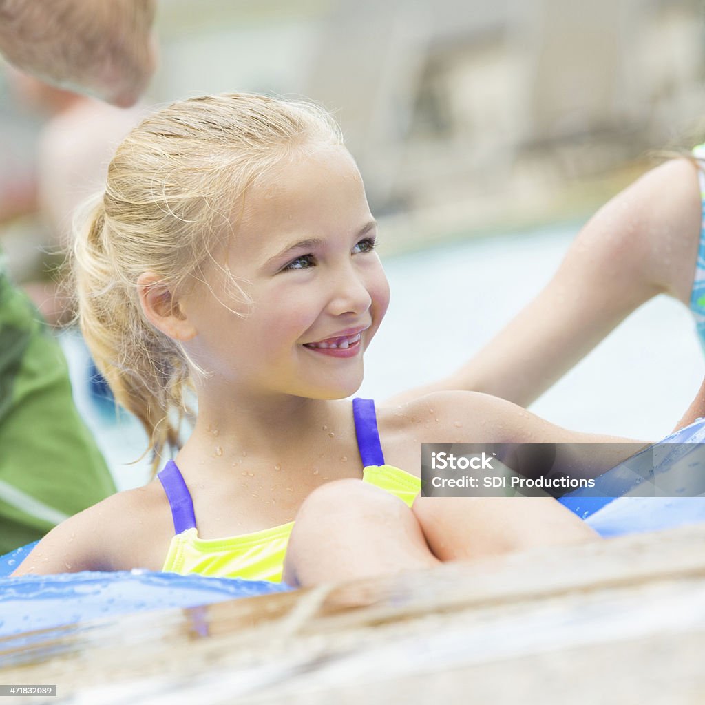 Linda niño de primaria niña flotando en la piscina mientras de juguete - Foto de stock de Familia libre de derechos