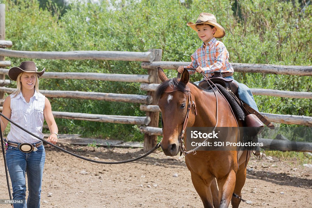 Joven mujer givng son Lecciones de equitación on ranch - Foto de stock de Adulto libre de derechos