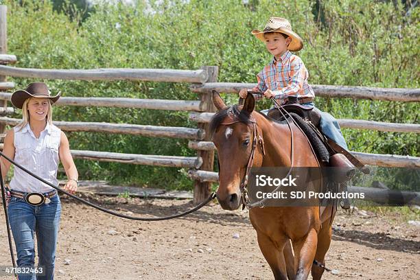 Mulher Givng Jovem Filho Cavalgar Lições No Rancho - Fotografias de stock e mais imagens de Adulto - Adulto, Agricultor, Animal