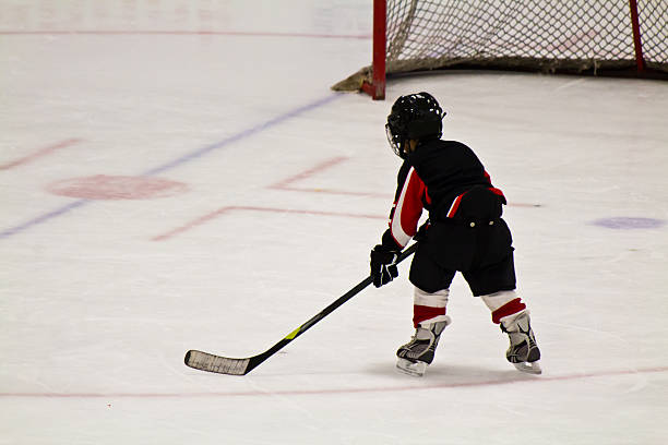 Child skating and playing hockey in an arena stock photo