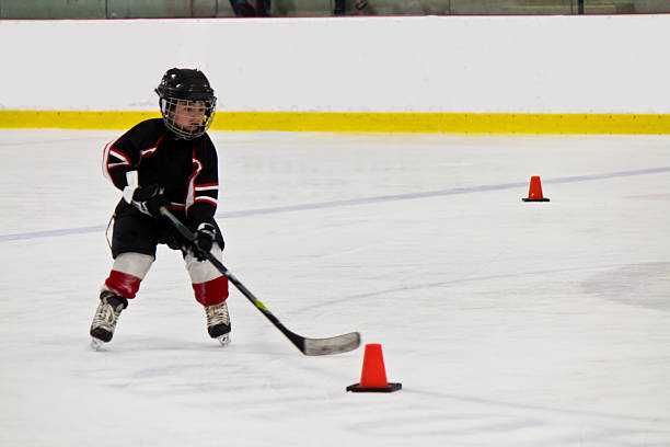 Child skating and playing hockey in an arena stock photo