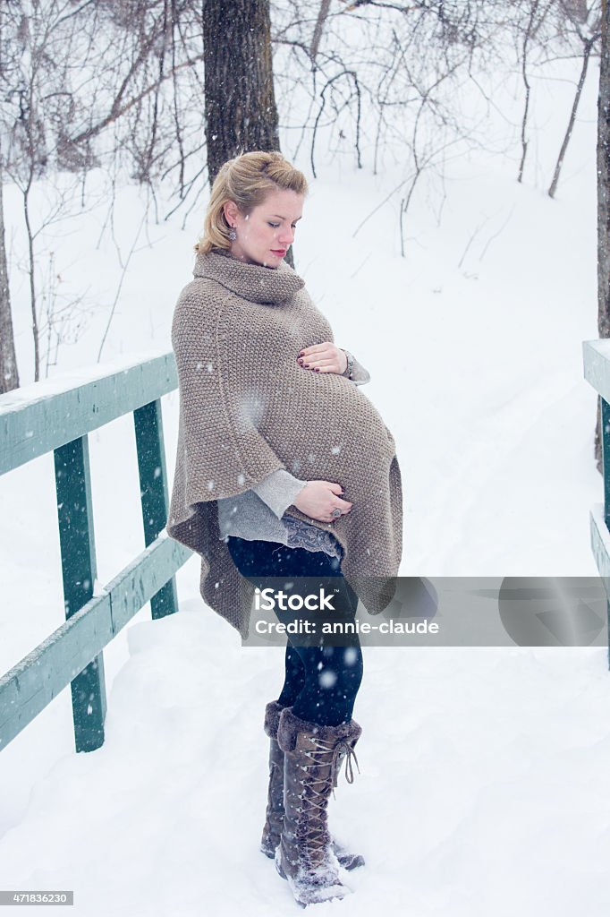 Pregnant woman posign in a snowy landscape A young pregnant woman posing in a park covered in snow while it is snowing Pregnant Stock Photo