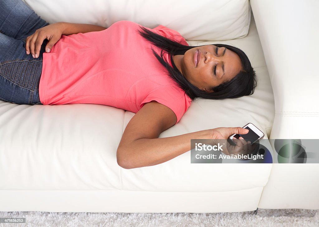 African American Woman Asleep on Couch with Phone Shot in Riverside, California in March of 2015. 2015 Stock Photo