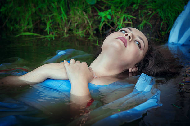 istock Young beautiful drowned woman lying in the water 471836320