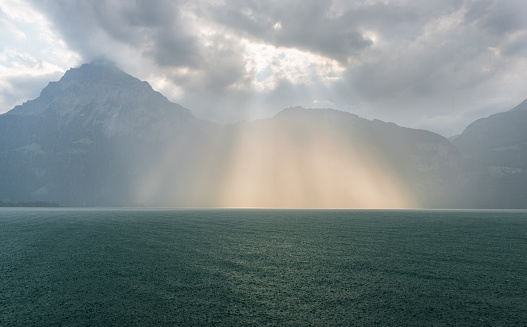 rays of light breaking through the clouds and fall to the water of the lake