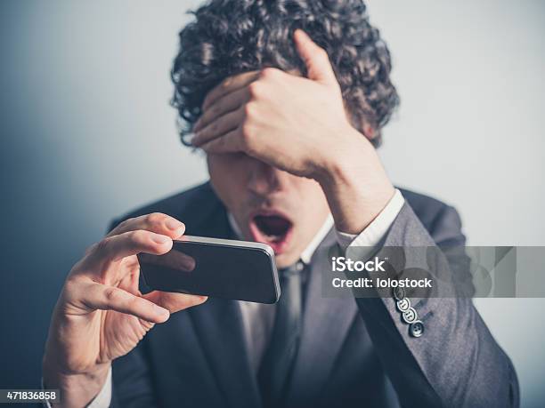Shocked Empresario Leyendo En Su Smartphone Foto de stock y más banco de imágenes de 2015 - 2015, Adulto, Adulto joven