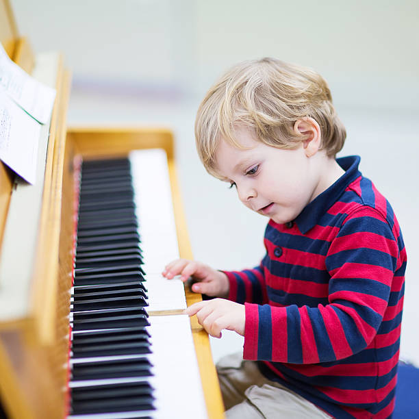 istock Two years old toddler boy playing piano, music schoool. 471837110