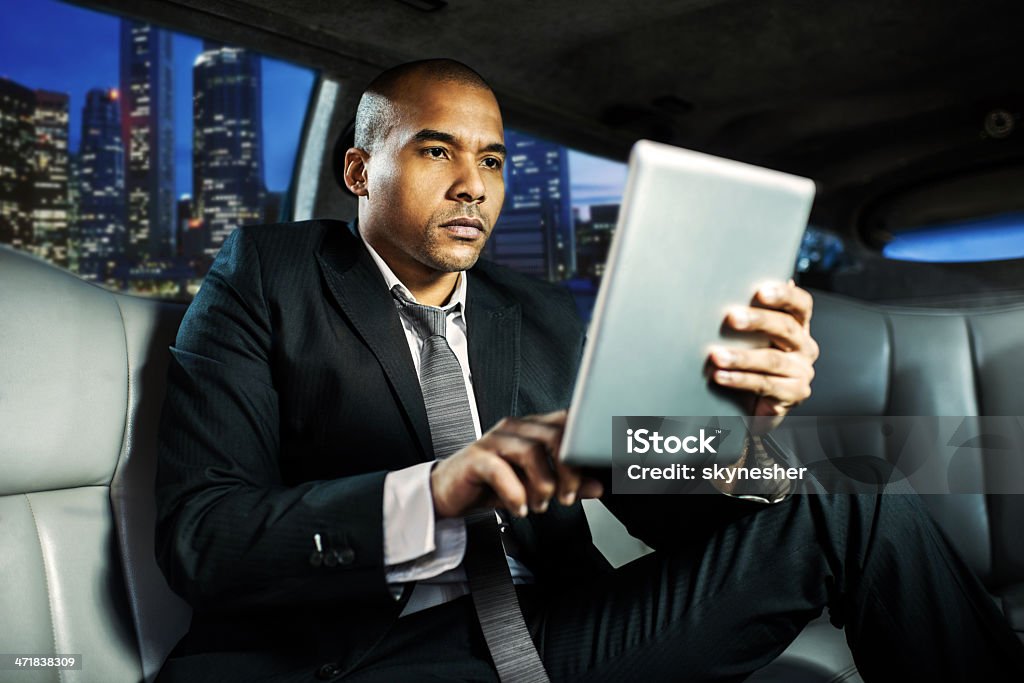Afro-américaine Homme d'affaires en limousine travaillant sur l'onglet numérique - Photo de Limousine - Voiture libre de droits