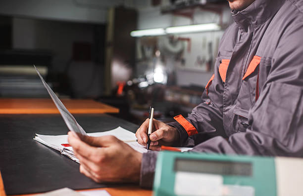 istock Unrecognizable manual worker writing a daily report in a workshop. 471838640