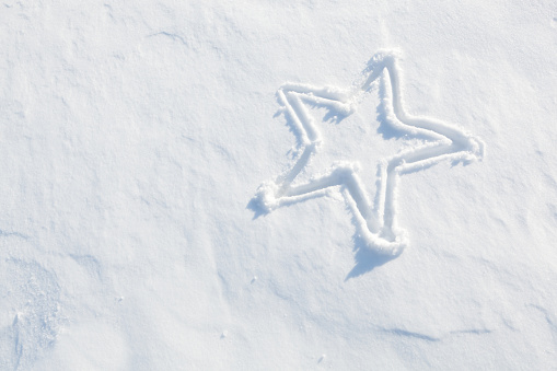 Subject: A Christmas star etched into a snowdrift on a sunny winter day.