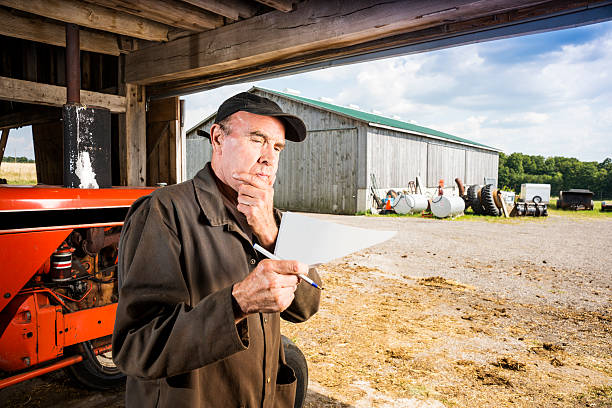 A farmer looks a paper document, letter or notes.