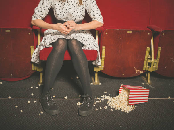 donna nel teatro con popcorn sul pavimento - sole of foot human foot women humor foto e immagini stock