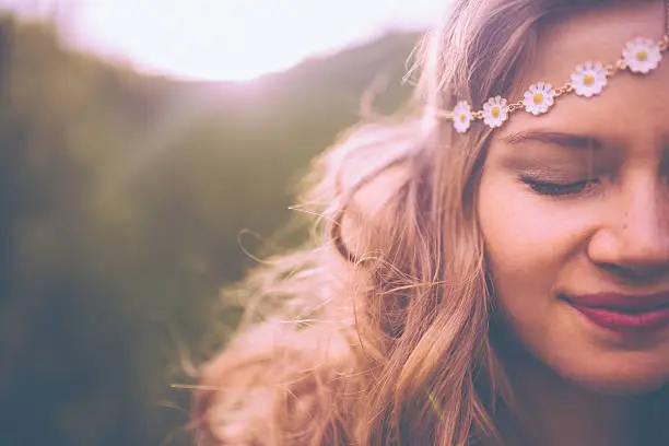 Closeup of a the face of a smiling boho girl wearing a vintage flowered headband