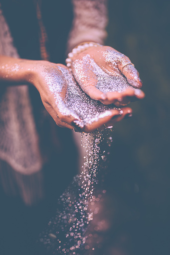 Vintage style shot of a woman's hands with silver glitter falling from them