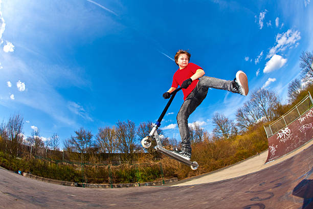 istock Boy riding scooter is jumping at a skate park 471842011