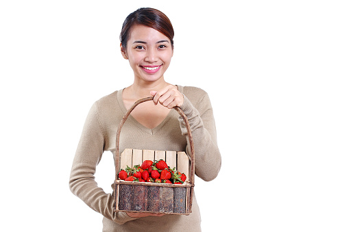 Young beautiful happy lady with a basket of strawberries. Isolated in white background. High key.