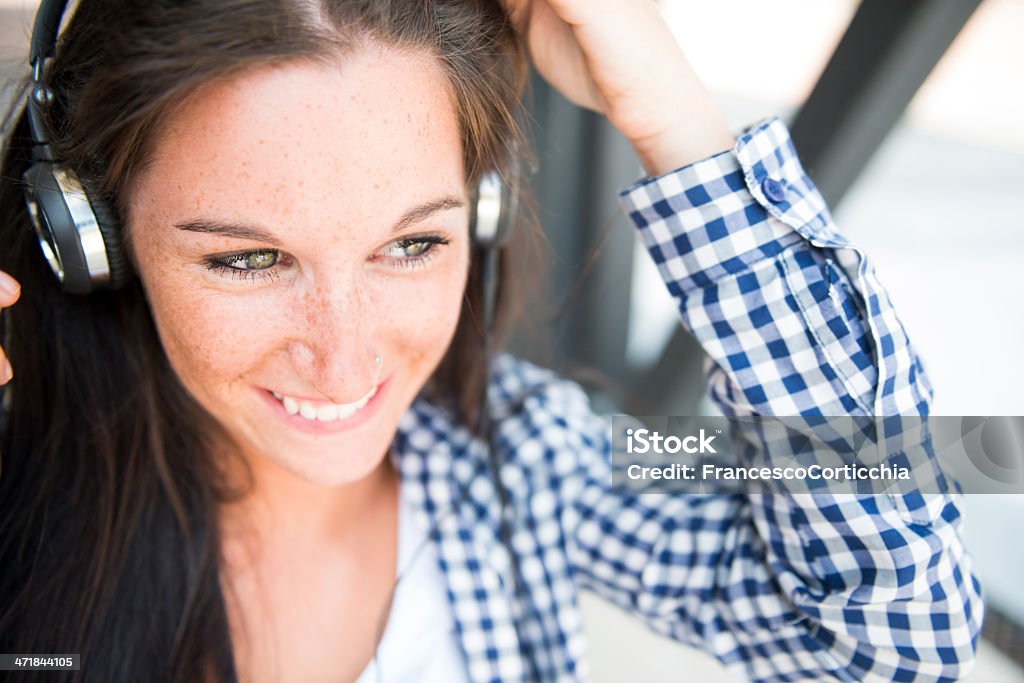 Young happy woman with ear phone Young happy caucasian woman listening music in the city with her modern ear phone. 20-24 Years Stock Photo