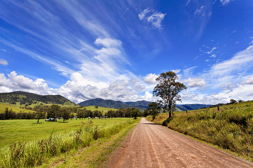 remote rural regional Australia, state NSW and unsealed gravel road going through developed argicultural properties towards mountains near Barrington Tops