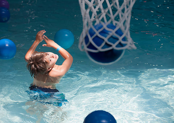 niño jugando al básquetbol en el parque acuático bajo techo - early teens child swimming pool swimming fotografías e imágenes de stock