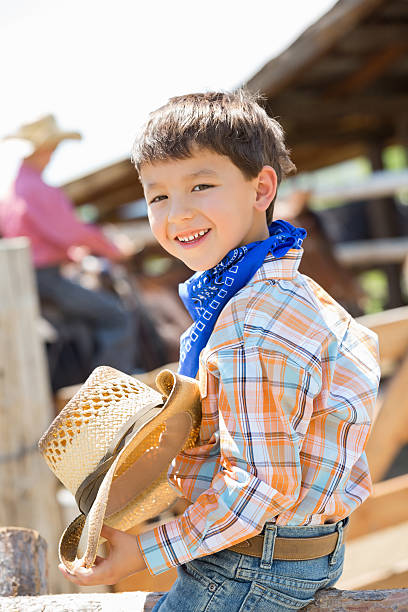 istock Cute young cowboy sitting on fencepost at ranch 471849247