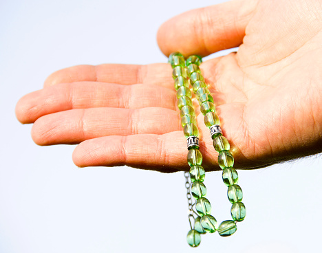 man holding green prayer beads