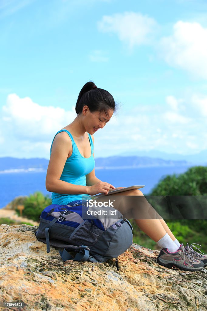 woman hiker use tablet pc outdoor woman hiker use tablet pc sit on seaside mountain rock Hiking Stock Photo