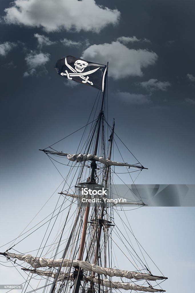 Navio pirata com bandeira Jolly Roger Leaning sob céu escuro - Foto de stock de Bandeira royalty-free