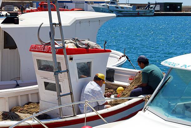 Garrucha, Spain - May 25, 2009: Spanish fishermen tending to their nets on traditional fishing boats in the harbour, Garrucha, Almeria Province, Costa Almeria, Andalusia, Spain, Western Europe.