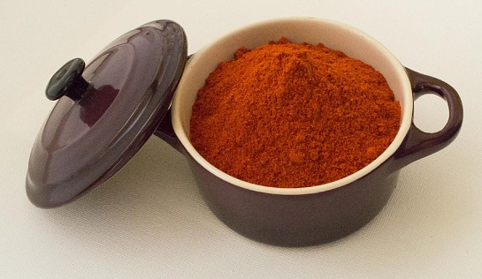 A bowl of chilli powder in an aubergine ceramic bowl with lid.