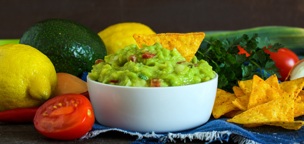 A bowl of guacamole served with plain crackers.