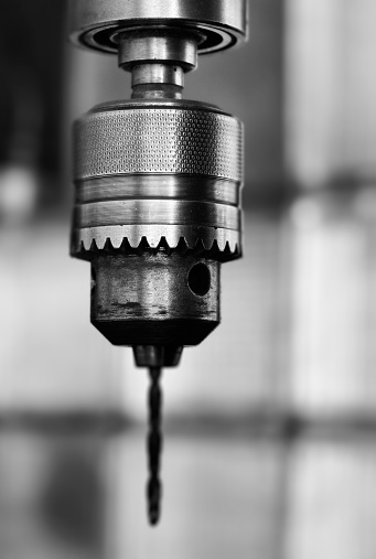 black and white picture of a drill head on a patterned blurry background