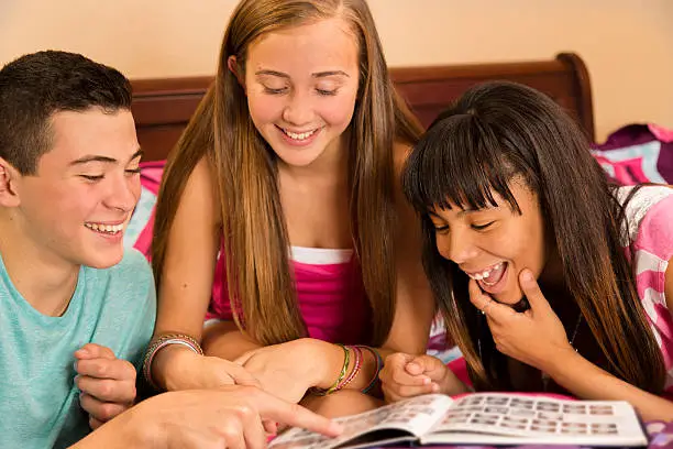 Three teenage friends look at school yearbook.  