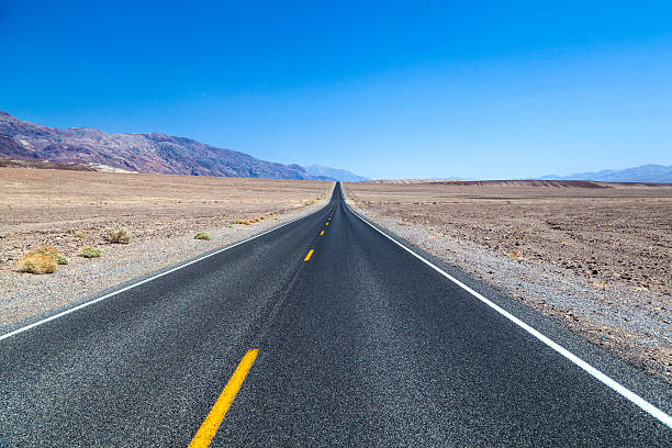 death valley road nel deserto - arid climate asphalt barren blue foto e immagini stock