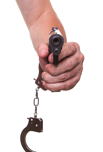 istock gun aimed at you in handcuffs isolated 471860872