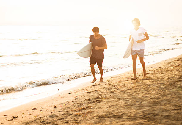 istock guys running on the beach with surfboard 471862407