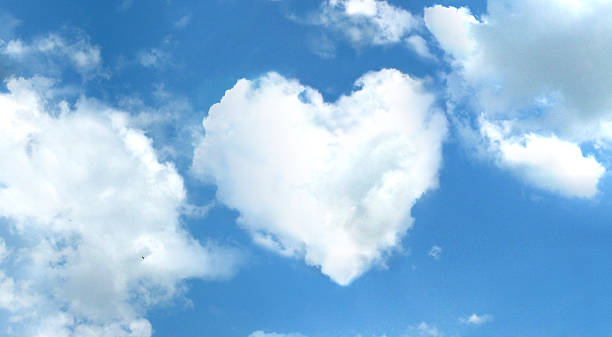 White, fluffy clouds forming a heart on a blue sky stock photo