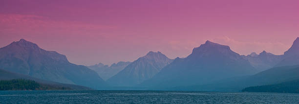 Hazy Mountains and Lake McDonald A purple haze covers the lake and blurs the view of the Continental Divide. This photograph was taken from Apgar Village on Lake McDonald in Glacier National Park, Montana, USA. jeff goulden glacier national park stock pictures, royalty-free photos & images