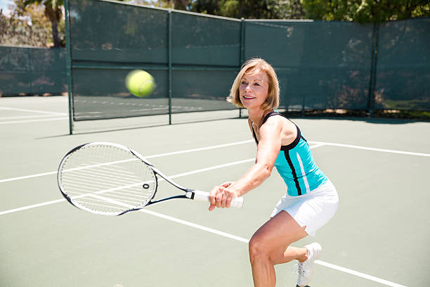 mujer madura jugando al tenis activo - tennis senior adult adult mature adult fotografías e imágenes de stock