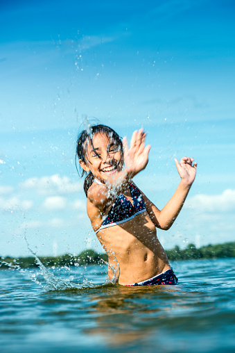 Girl standing in lake and splashing water