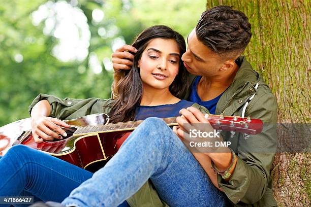 Amorevole Giovane Coppia Seduta Sotto Un Albero Con Chitarra - Fotografie stock e altre immagini di 20-24 anni