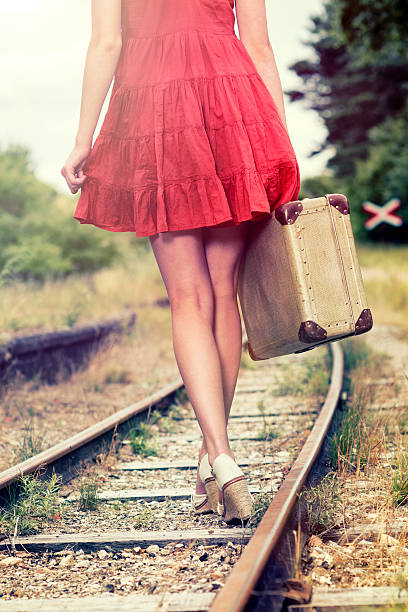 istock Woman walking on railroad tracks with suitcase 471868299
