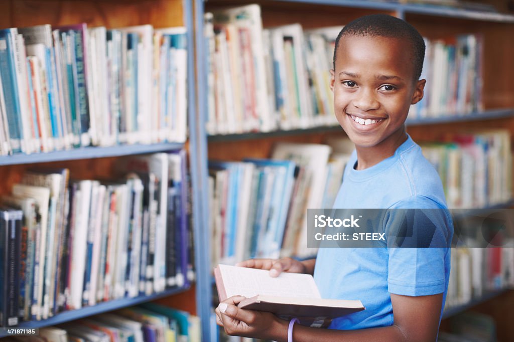 Stories are like new playgrounds! Portrait of an african american boy enjoying a good book at the library Reading Stock Photo