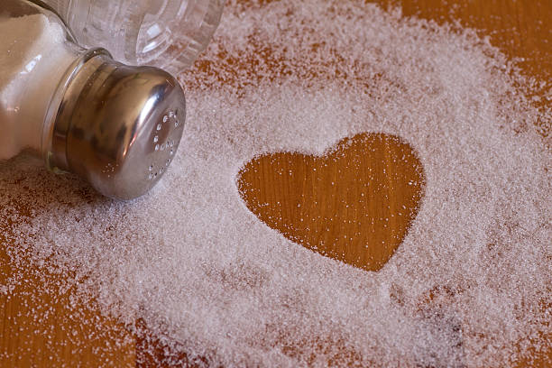 Salt and heart shape on wooden table with salt shaker stock photo